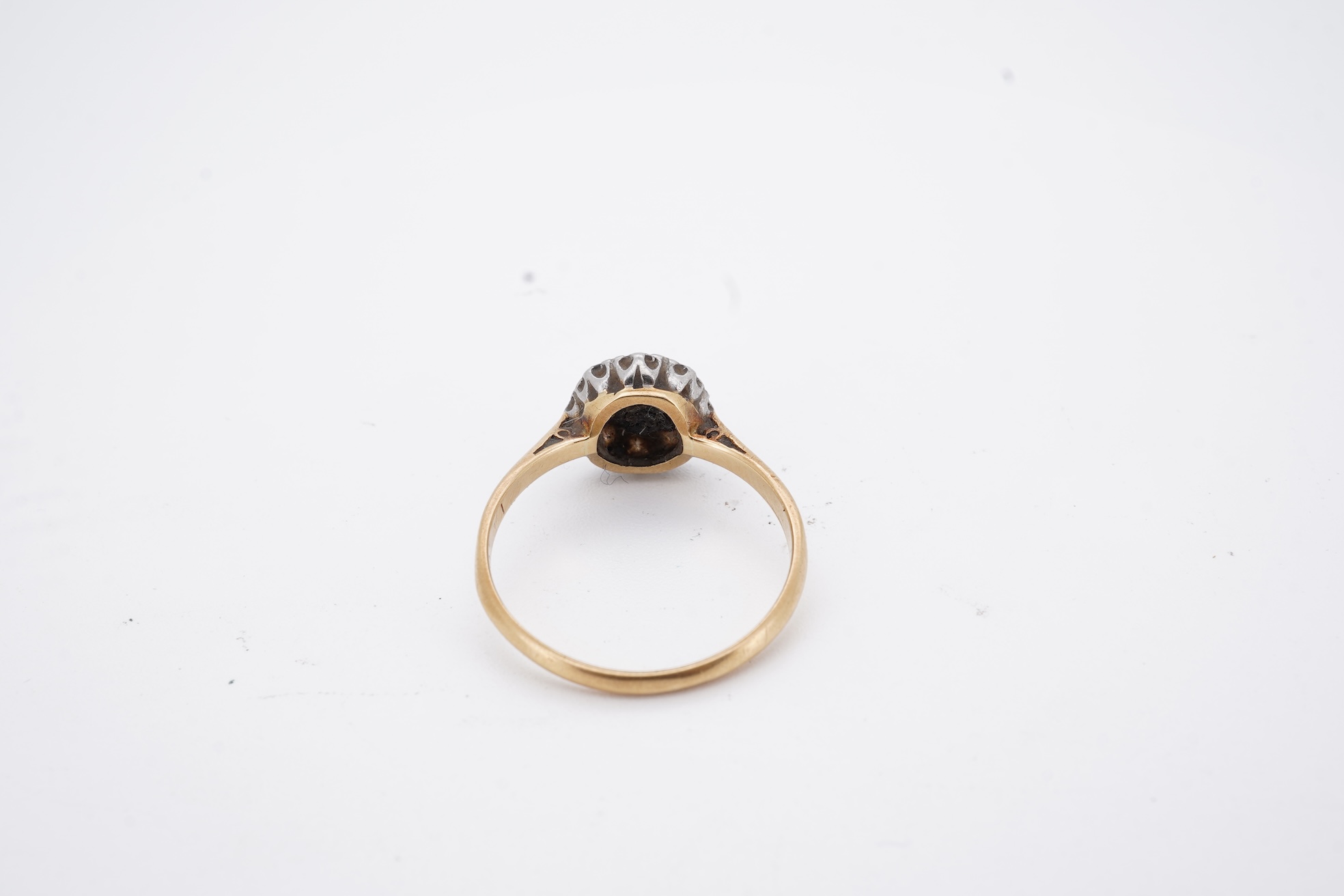 An early 20th century 18ct, plat. and nine stone diamond cluster ring, the central diamond weighing approximately 0.30ct, size Q, gross weight 3.1 grams.